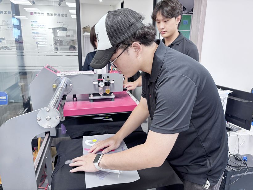 實習生依客戶需求對位，將圖樣燙印於衣服